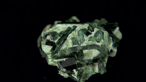 rotación sin problemas de un mineral verde oscuro (actinolita) frente a un fondo negro