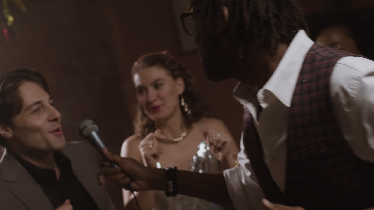 People enjoying karaoke and singing with a microphone at a party