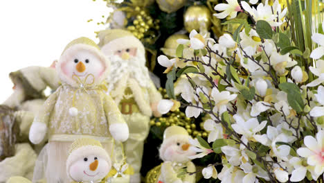 cute snowmen family dolls and santa clauss near christmas tree and flowers