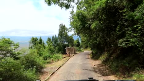 vehículo de safari conduciendo por una carretera pavimentada hasta la caldera de ngorongoro, disparado desde un coche
