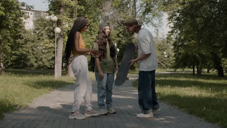 friends with a skateboard talking in a park