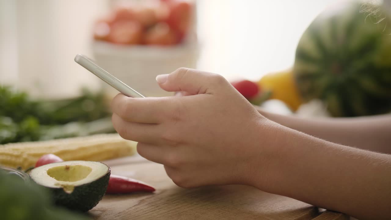 vista de mano de una mujer usando el teléfono móvil en la cocina/rzeszow/polonia