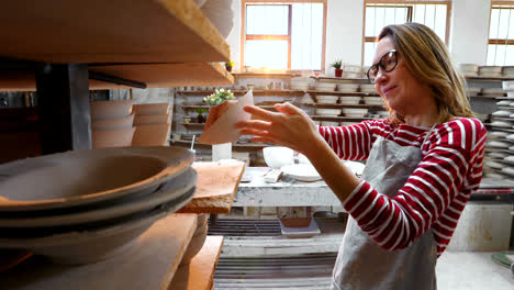 Female-potter-arranging-bowl-in-shelf-4k