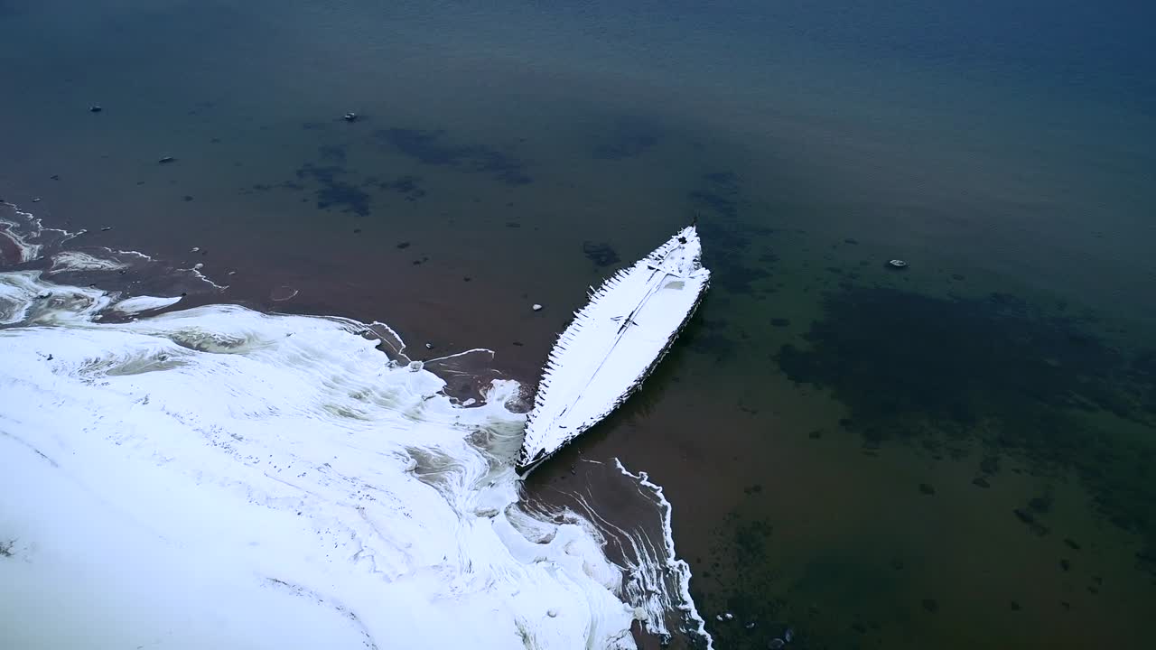 Vista aerea di un relitto di legno coperto di neve sulla spiaggia di Kasispea