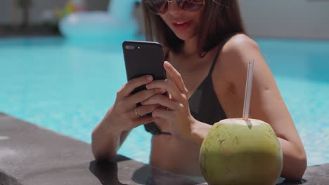 mujer relajándose junto a la piscina con una bebida de coco