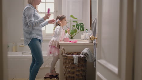 happy mother brushing daughters hair in bathroom cute little girl getting ready in morning loving mom enjoying parenthood caring for child