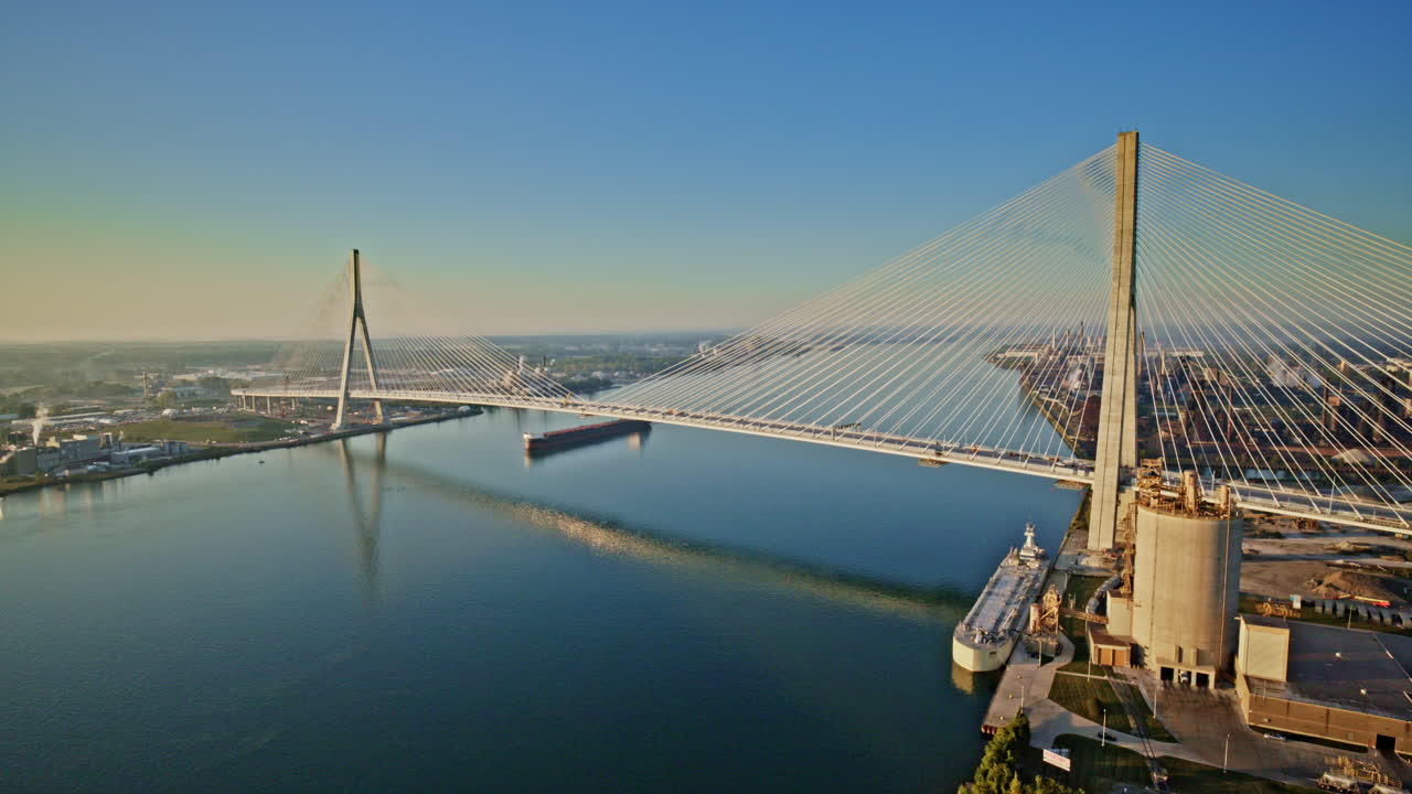 Drone shot showcasing a freighter cruising through the river beneath the Gordie Howe International Bridge