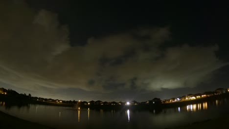 Wolken-Ziehen-In-Diesem-Tag-zu-Nacht-zu-Tag-Zeitraffer-In-Verschiedene-Richtungen-über-Den-Himmel,-Wobei-Der-Himmel-Und-Die-Wolken-Vom-See-Reflektiert-Werden