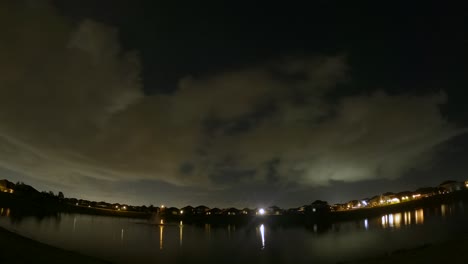 las nubes cruzan el cielo en diferentes direcciones en este lapso de tiempo del día a la noche con el cielo y las nubes reflejándose en el lago