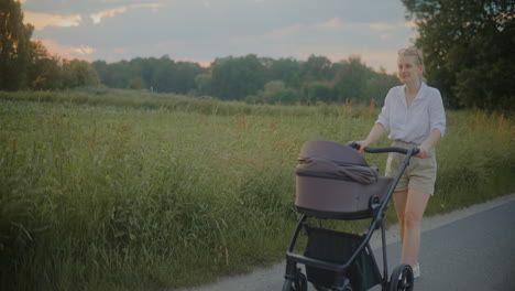 young mother walks with stroller at sunset