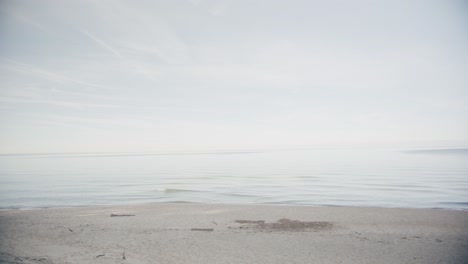 pan along clean sand shore in the fall with calm water