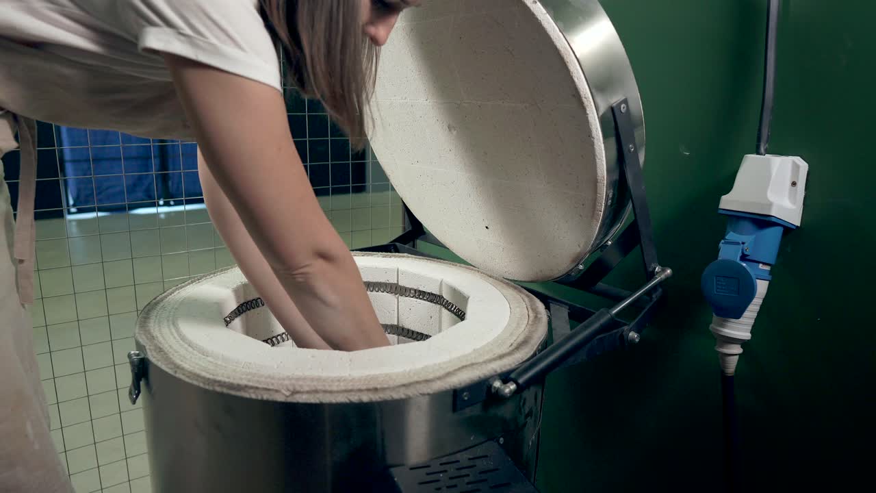 오븐 에 도자기 를 넣고 있는 여자