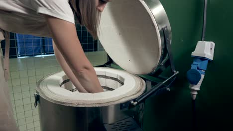 mujer colocando cerámica en un horno