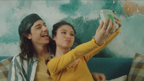 couple playing video games and taking selfies at home