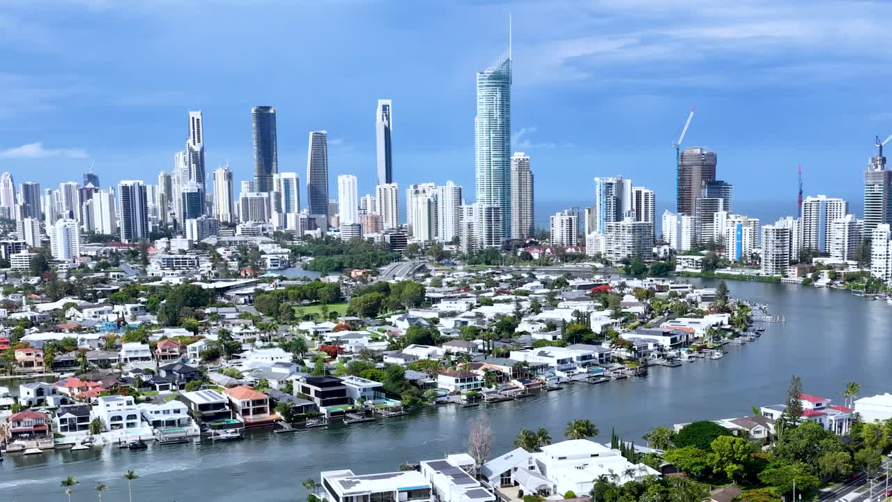 Daytime drone shot pans across canal, luxury homes, marina, and modern Gold Coast skyline