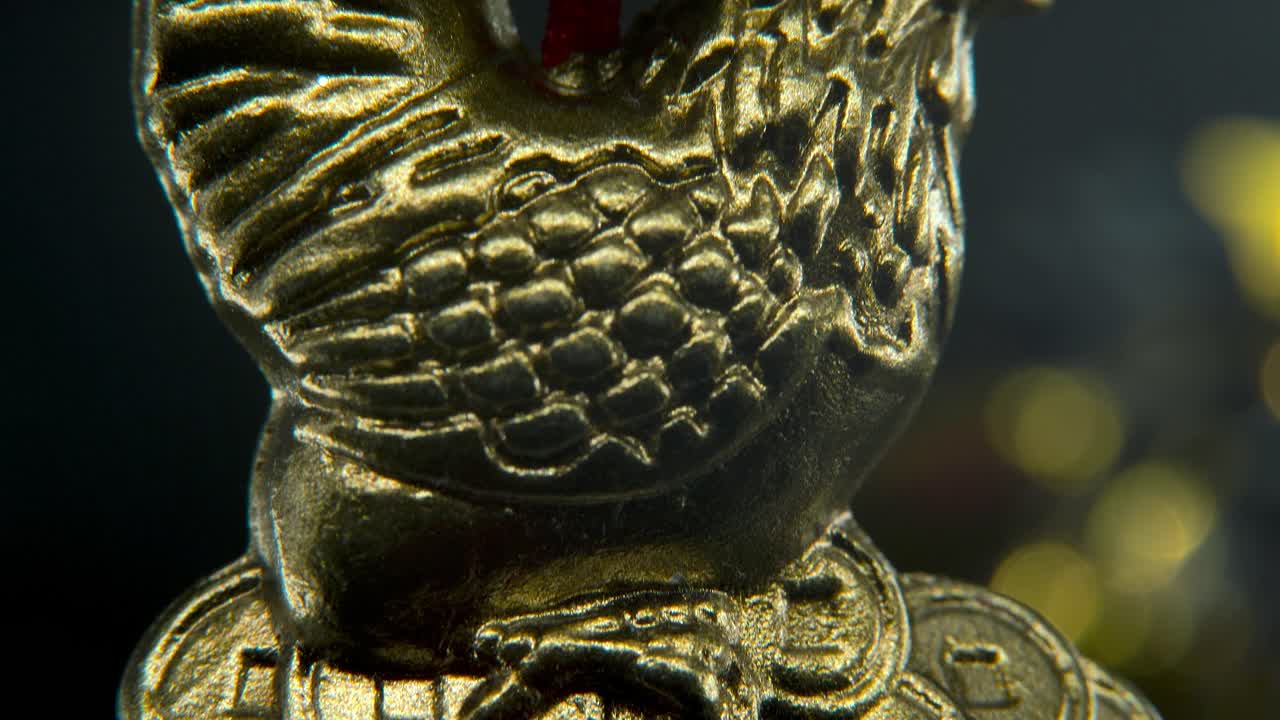 año nuevo chino tradicional pollo dorado estatua del zodiaco, gallo de oro colgado sentado en monedas de dinero símbolo asiático, fondo brillante con profundidad de campo borrosa, macro cinematográfico inclinado hacia arriba video 4k
