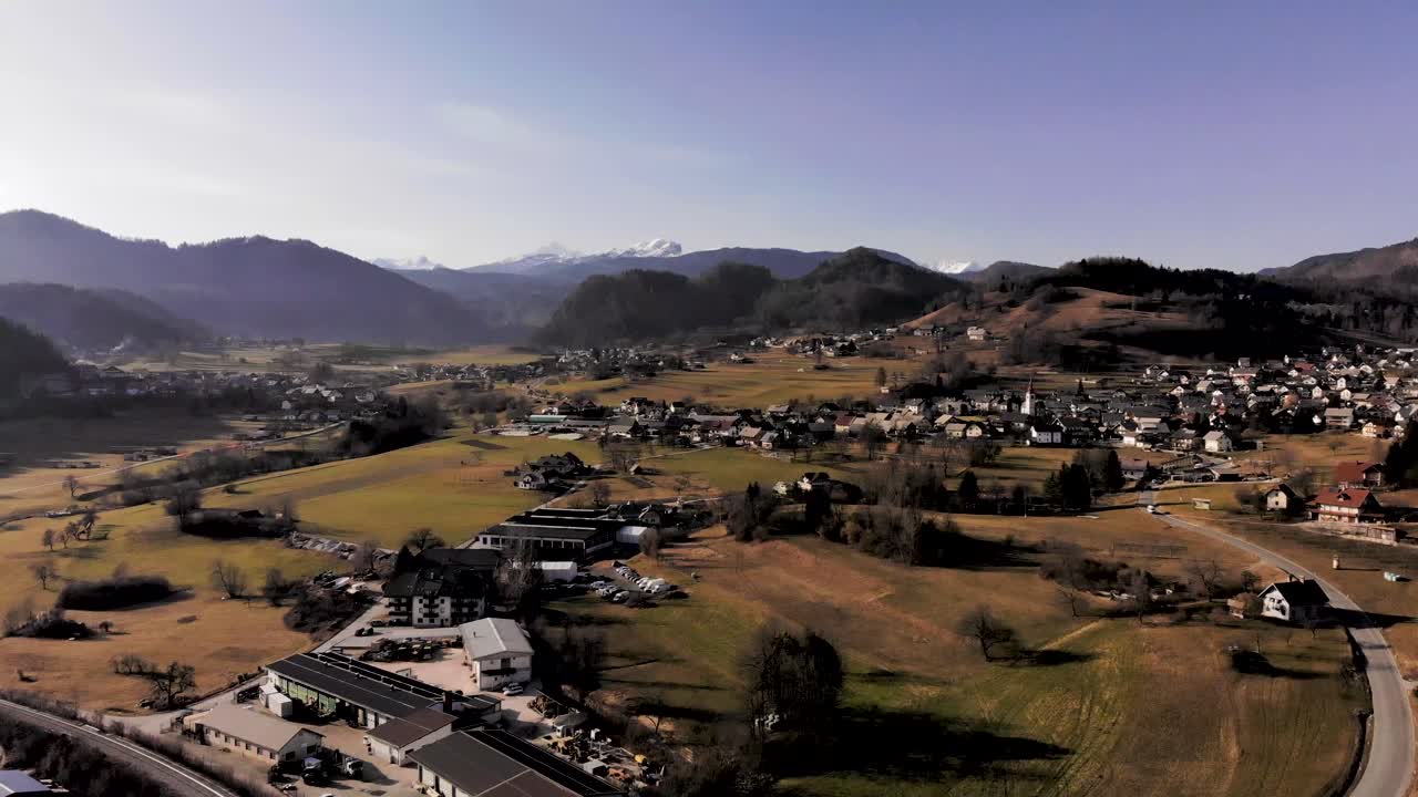 Aerial flight over a village in the mountains of the Julian Alps. Bright sunny day in Slovenia with a small village nestled in the Mountains