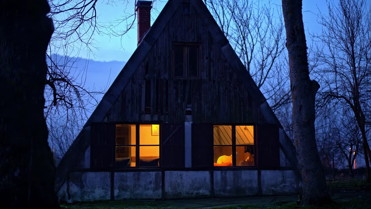 A-Frame-Hütte in der Dämmerung mit warmem Licht in den Fenstern
