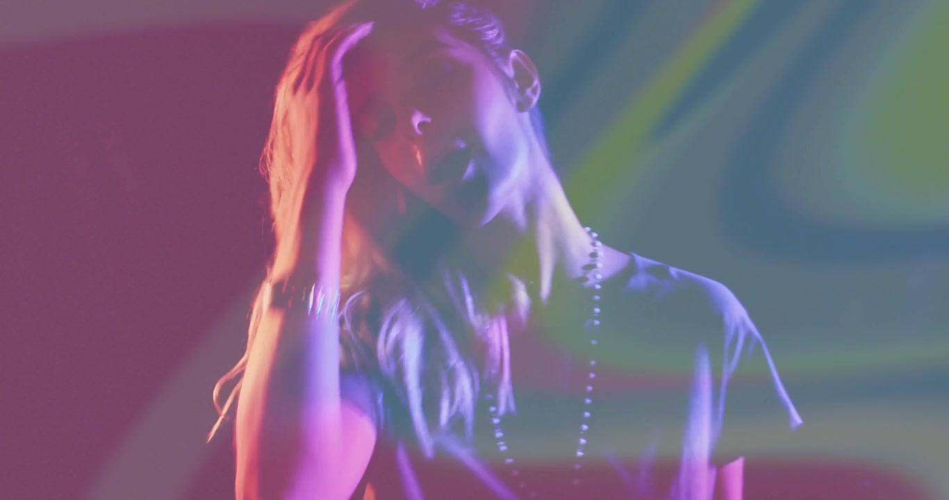 Claviériste initiant une performance musicale en jouant des touches sous des lumières colorées, puis se brossant les cheveux.
