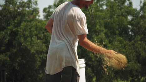 joven agricultor que enriquece el suelo de la granja arrojando fertilizante en polvo en forma seca