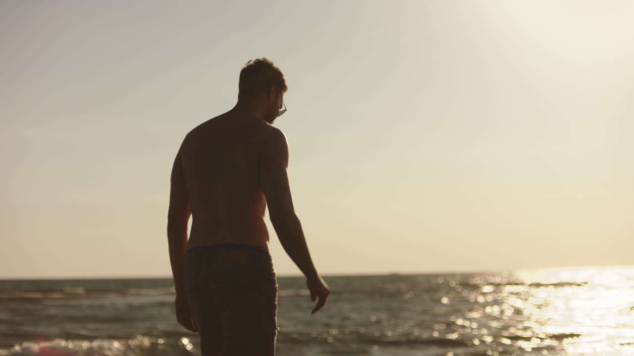 해가 지는 동안 해변에 있는 남자