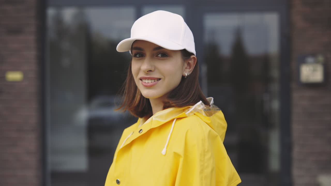 Woman wearing a yellow raincoat and white baseball cap