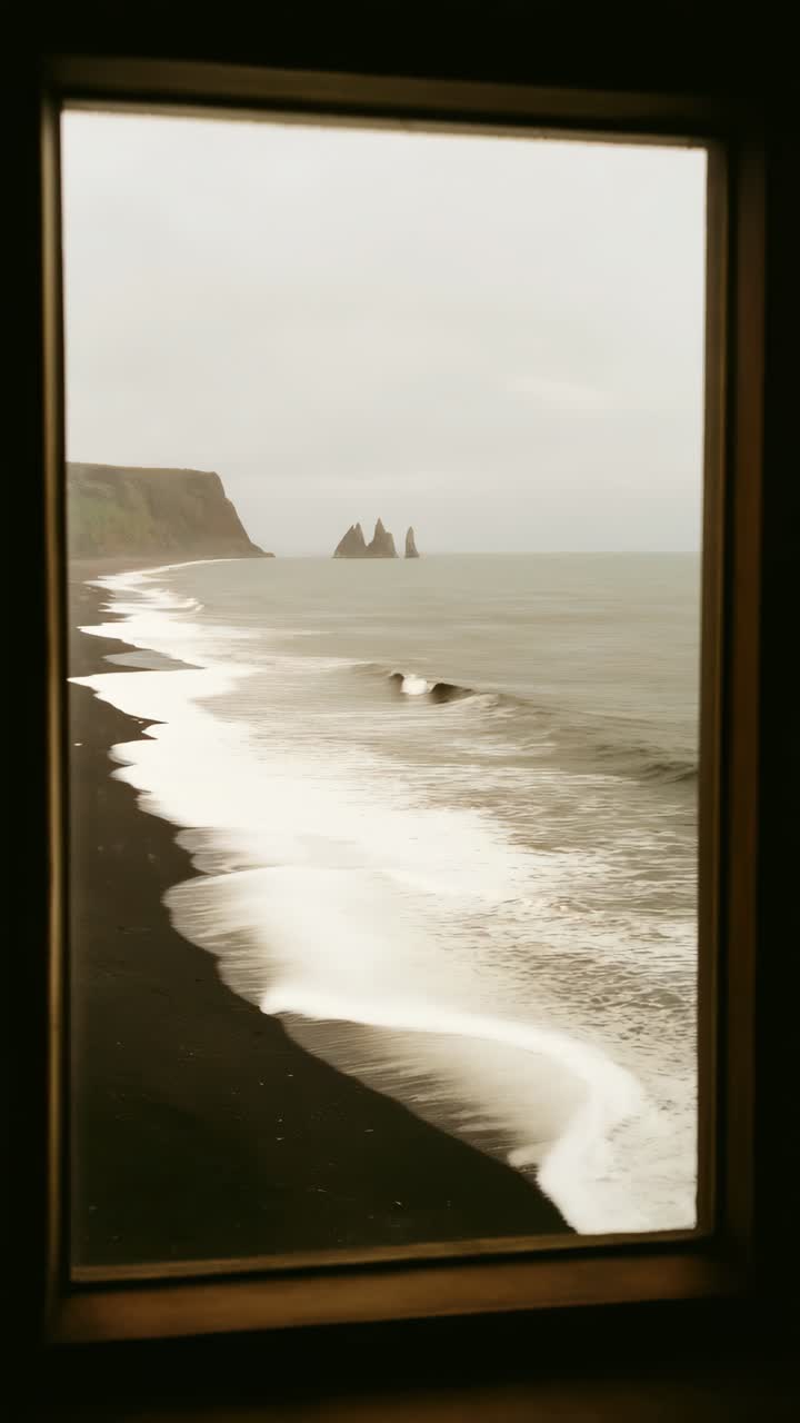 Vista da una finestra che si affaccia su una spiaggia di sabbia nera e faraglioni