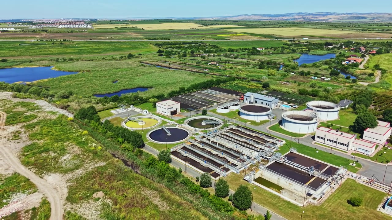 Water treatment facility near green fields and water bodies during bright day with clear skies in a rural setting