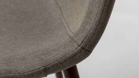 Slow-zoom-on-fabric-seam-of-upholstered-chair,-macro-shot-against-white-backdrop