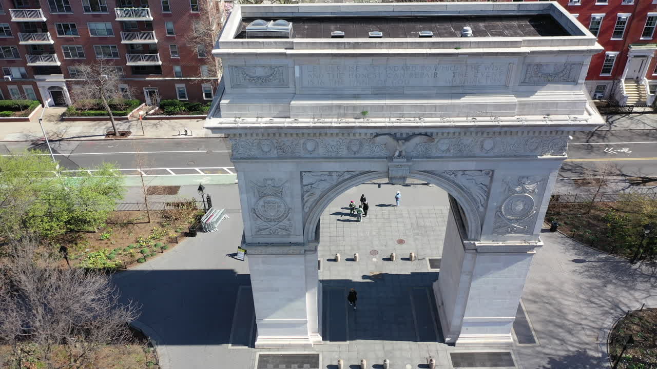 Starting from the top, a high angle view looking down as the camera dolly out, rises up, pans right from the Washington Square Arch in NYC. The park is mostly empty - it's a bright - sunny day.