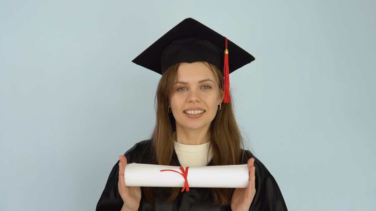 joven estudiante con una bata negra y un sombrero de maestría sostiene en sus manos en una posición horizontal un diploma de educación superior. fondo blanco