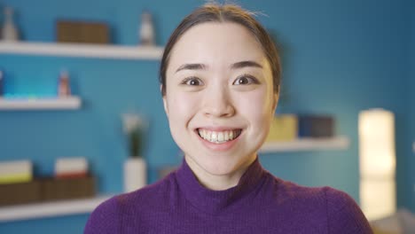 standing serious asian woman raises her head to camera and smiles.