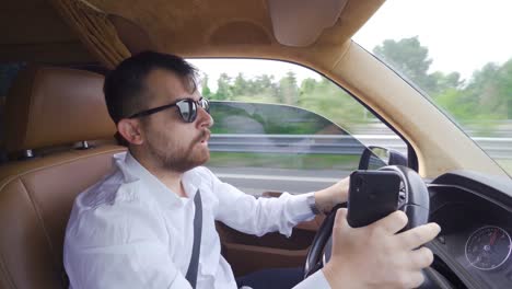 hombre de negocios sumergiéndose en el teléfono mientras conduce.