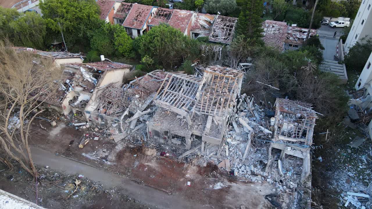 Circular drone shot captures the aftermath of missile strikes on homes in Tel Aviv. The structures are barely standing, with only wooden beams left intact amid widespread devastation