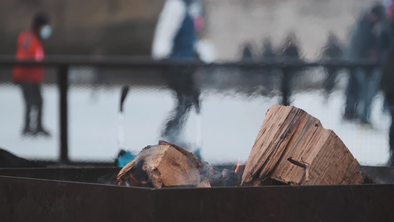 Close up of warming fire at outdoor ice skating rink. Skaters in background.