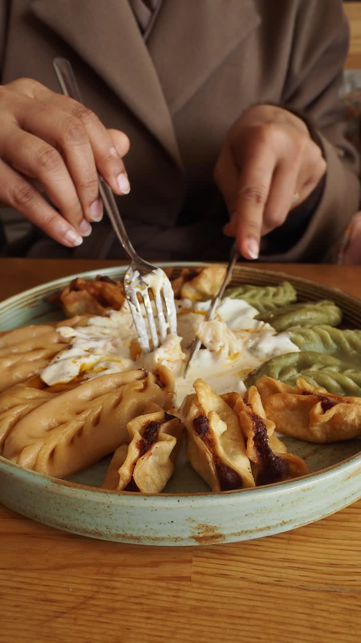 Close-up of Hands Eating Delicious Dumplings with Yogurt Sauce