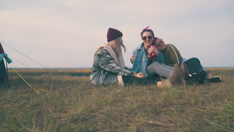 cheerful women cover friend with denim jacket at tent