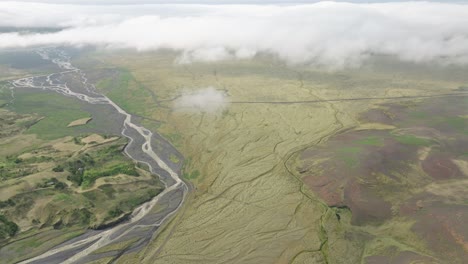 aerial view of a braided river system flowing through expansive plains in hafursey, iceland, under low clouds, with patches of green terrain and volcanic features.
