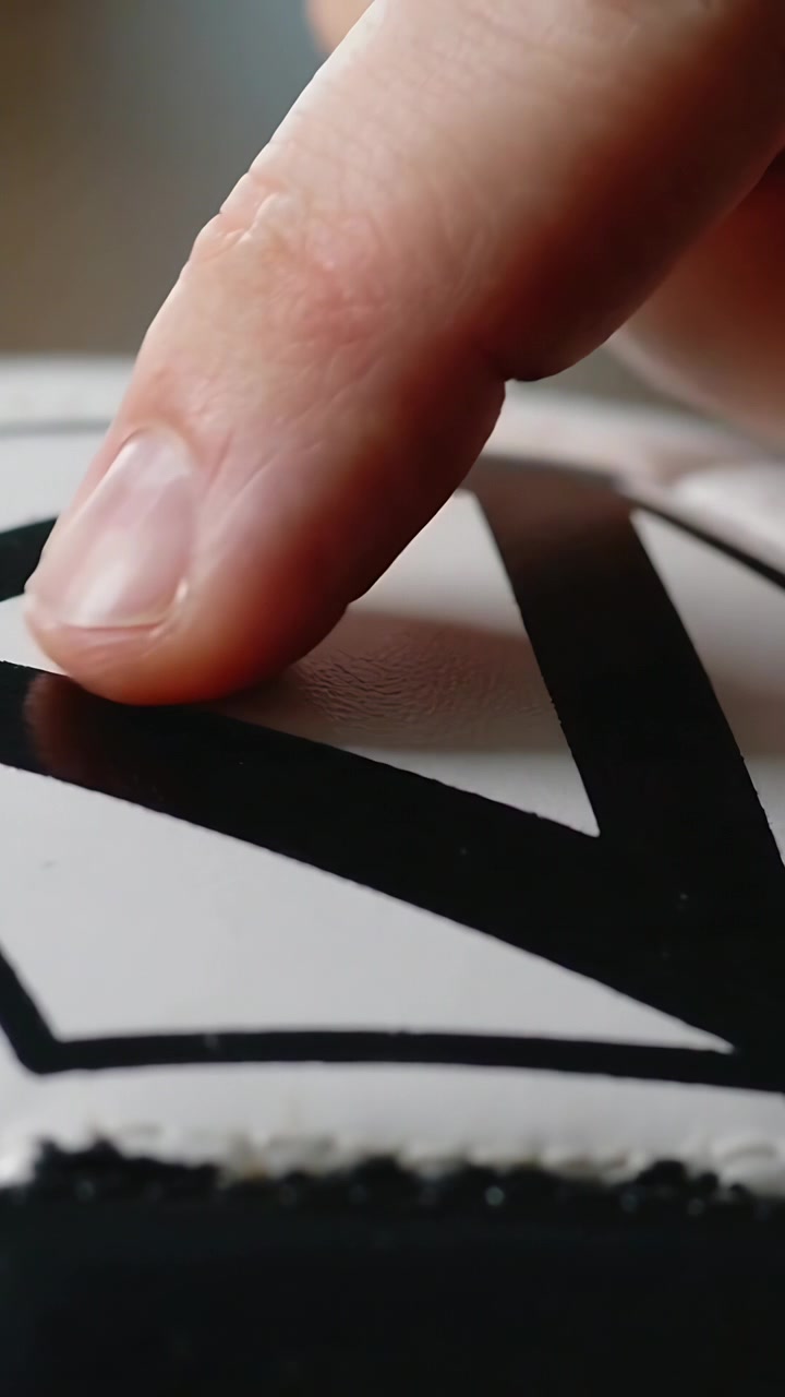Vertical video: Moving to tap index tip sliding along black print on white object at table, feeling