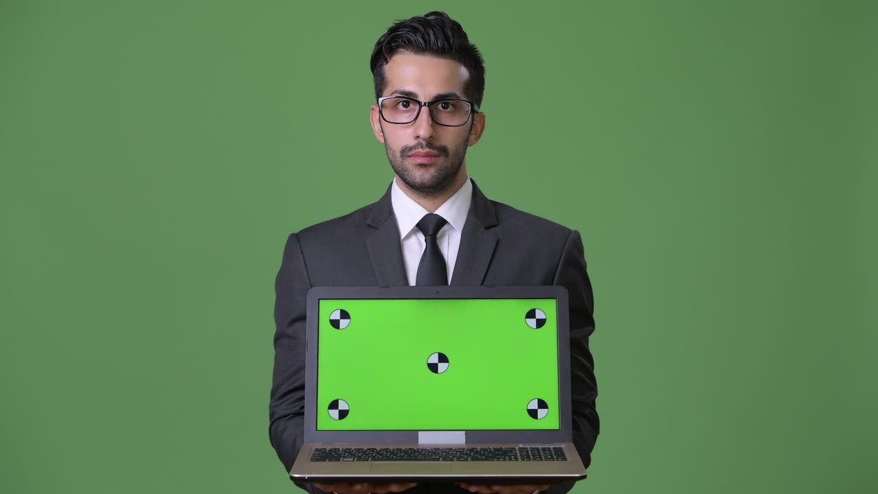 joven empresario persa barbudo y guapo contra un fondo verde