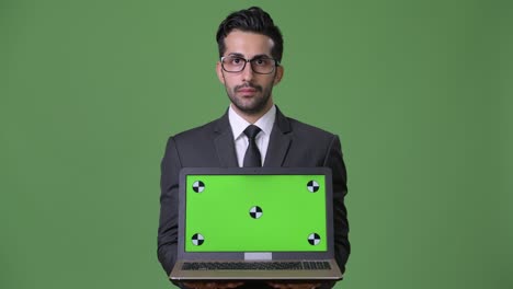 joven empresario persa barbudo y guapo contra un fondo verde