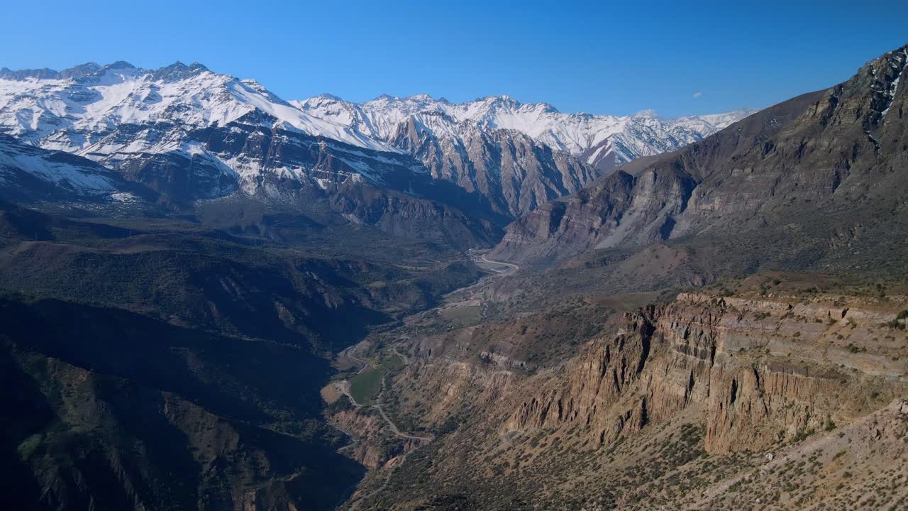Forward flight over barren ridge toward snow capped mountain range