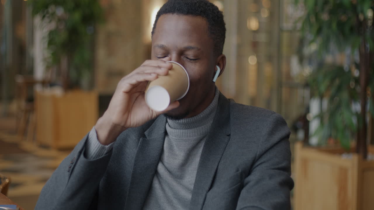 Man drinking coffee in a cafe and smiling