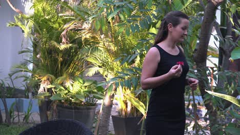 plano medio de una hermosa joven jugando con una flor mientras explora los terrenos del hotel tropical