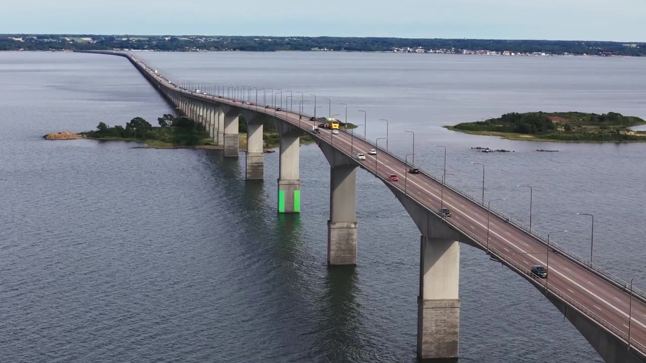 Auto e un autobus giallo che passano sulla cima del ponte di Öland, vista da drone.
