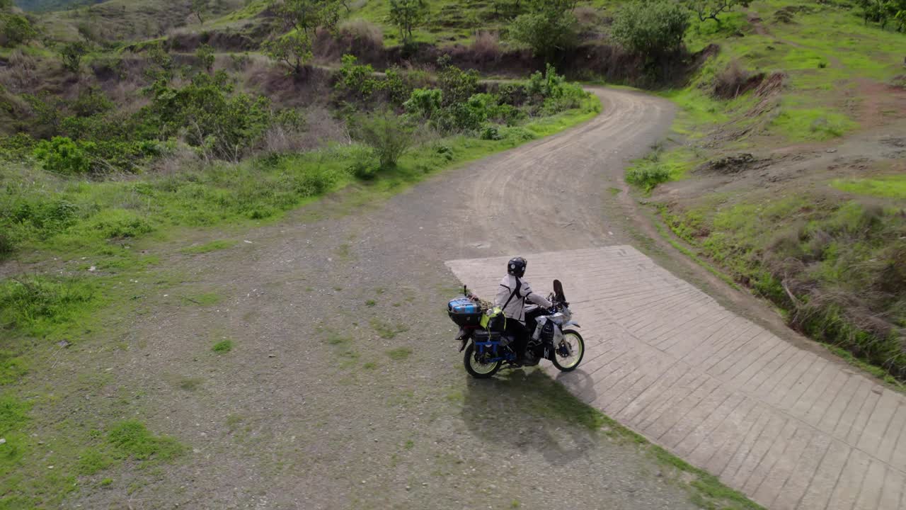 Drone tracking a motorcyclist riding through a lush green off-road landscape in Venezuela