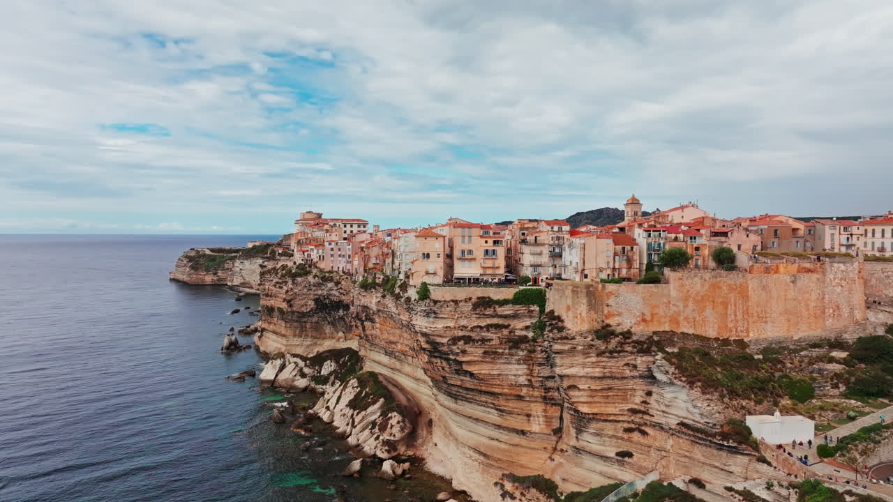 Aerial drone shot over the historic coastal town of Bonifacio in Corsica, France. High view of the rocky steep cliff and the turquoise sea. Ancient Citadel overlooking the rugged coastline