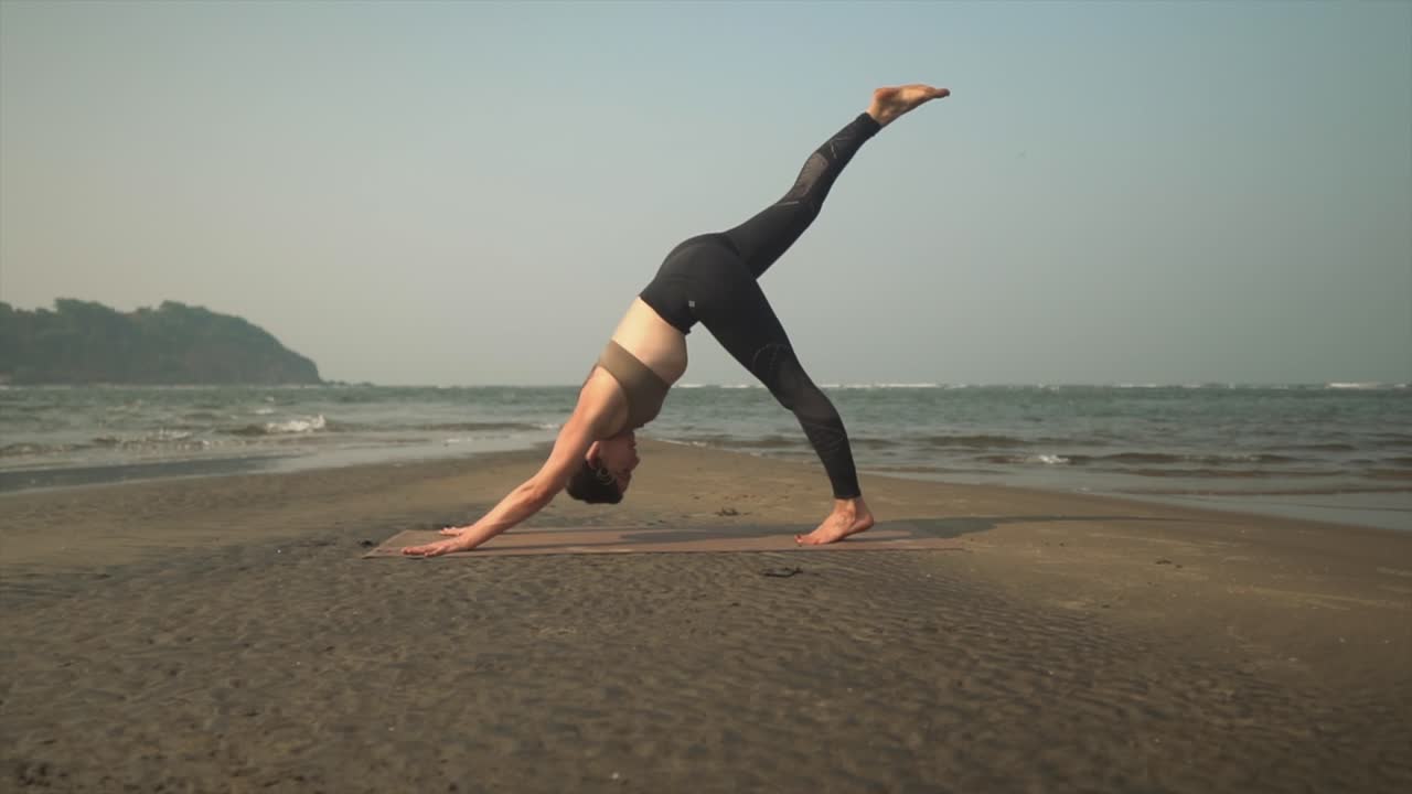 mujer profesional haciendo ejercicios de yoga en la orilla de una playa