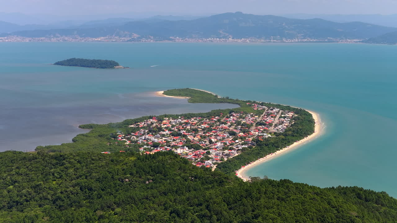Cảnh quay trên không từ phía trước bãi biển Praia da Daniela ở Florianopolis, thể hiện bán đảo và biển xanh êm đềm.