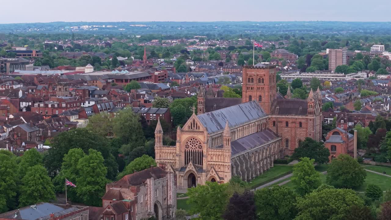 Smooth orbiting drone footage of St Albans Cathedral framed by the city skyline and vibrant green landscape